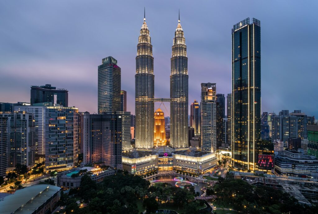 The Petronas Towers lit up at night above a park in Kuala Lumpur