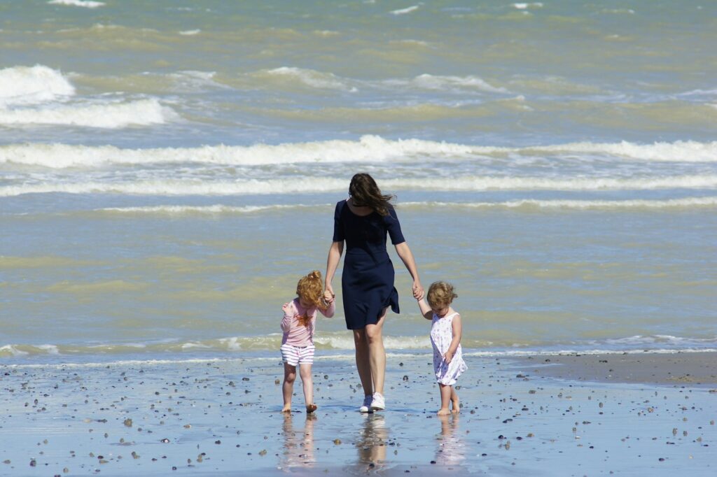 A mother walking with two children along the beach